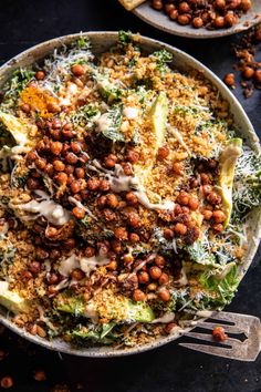 a bowl filled with lots of food next to a fork and some crackers on the side