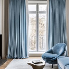 a living room filled with furniture and a large window covered in blue drapes