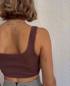 the back of a woman's top with a chain on her neck and shoulder