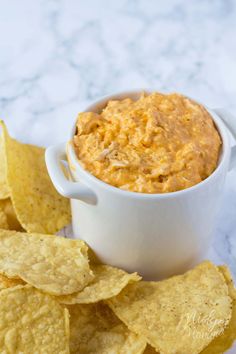 a white bowl filled with dip surrounded by tortilla chips