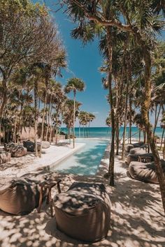 the beach is lined with palm trees and bean bag loungers in front of the water