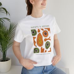 Our Papaya & Avocado design t-shirt was handmade in Canada and assembled with Printify. The design includes written text and controller icons. The t-shirt colour options include white and ash grey. The t-shirts are unisex sizing; perfect for everyone! If you are unsure of sizing, please refer to the size guide in the pictures.  This classic unisex jersey short sleeve tee fits like a well-loved favorite. Soft cotton and quality print make users fall in love with it over and over again. These t-shirts have-ribbed knit collars to bolster shaping. The shoulders have taping for better fit over time. Dual side seams hold the garment's shape for longer.  .: 100% Airlume combed and ringspun cotton (fiber content may vary for different colors) .: Light fabric (4.2 oz/yd² (142 g/m .: Retail fit .: T White Organic Cotton T-shirt With Graphic Design, Unisex White Graphic Design Shirt, Unisex White Cotton T-shirt, White Organic Cotton Top With Graphic Print, Unisex White Graphic Tops, Unisex White Graphic Design Top, Unisex White Organic Cotton T-shirt, White Graphic Design Unisex Tops, Unisex Organic Cotton T-shirt With Graphic Print