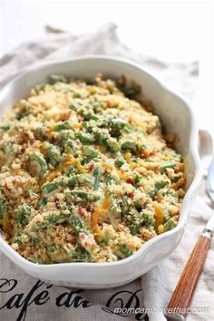 a casserole dish filled with green beans, cheese and other toppings on a table