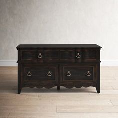 an old black dresser with two drawers on the bottom and one drawer open, in front of a white wall