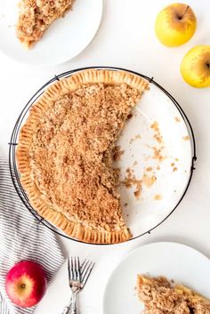 an apple crumb pie on a plate next to two plates with slices cut out