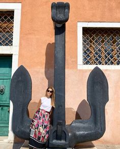 a woman standing in front of a large anchor