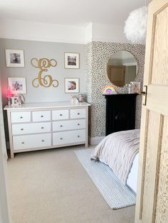 a bedroom with a dresser, mirror and pictures on the wall