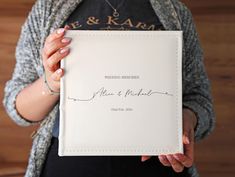 a woman holding up a wedding album with the word's name written on it