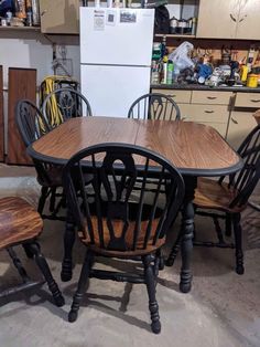 a kitchen table with six chairs and a refrigerator in the back ground, next to it