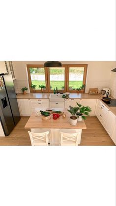 an aerial view of a kitchen with white cabinets and wood floors, including a table in the center