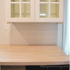 an empty kitchen with white cabinets and wood counter tops