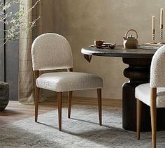 a dining room table with two chairs and a potted plant