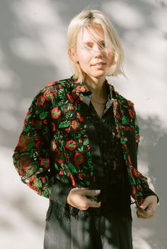 This unlined Olivia Jacket is sewn from an embroidered tulle. The embroidery features large bright red florals and greens resembling three dimensional pea shoots and florals. Paired with a black cotton cuff, and little buttons. Deadstock buttons down front and on cuffs Deadstock textile & cotton cuffs Double needle stitching throughout Cropped fit Relaxed fit through arms Sewn here in Los Angeles, CA Dry Clean only when needed 100% deadstock tulle with cotton embroidery. Deadstock shell buttons. Spring Party Outerwear With Floral Embroidery, Spring Red Outerwear With Floral Embroidery, Spring Floral Embroidered Red Outerwear, Red Floral Embroidered Outerwear For Spring, Red Outerwear With Floral Embroidery For Spring, Festive Black Spring Outerwear, Spring Party Embroidered Outerwear, Pea Shoots, Cropped Coat