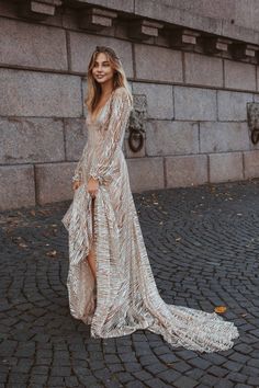 a woman in a long dress standing on a cobblestone street