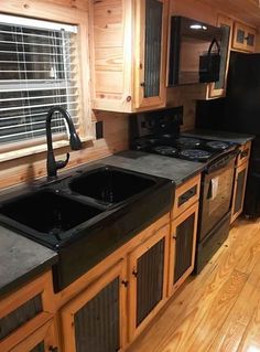 a kitchen with wooden cabinets and black appliances in the center, along with wood flooring