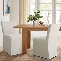 a dining room table with two chairs and a vase on the table next to it