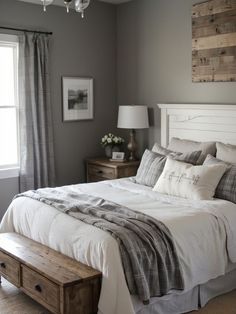 a white bed sitting next to a window and a wooden bench in front of it