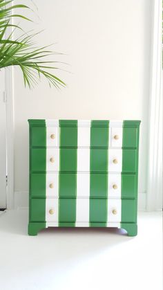 a green and white dresser next to a potted plant