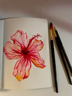 an open book with two pencils next to it and a flower painted on the page