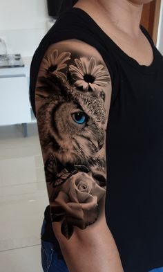 an owl with blue eyes and flowers on his arm is shown in this tattoo artist's photo