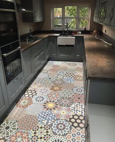 a kitchen with grey cabinets and colorful tiles on the counter tops, along with an oven