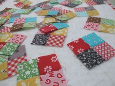 many small patchwork pieces are laid out on the floor