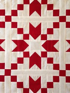 a red and white quilt with an arrow on it