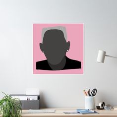 a man's face is shown on a pink and black poster above a desk