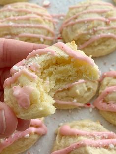 a close up of a person holding a doughnut with pink frosting on it