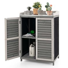 an outdoor storage cabinet with plants on top and two doors open to show the inside