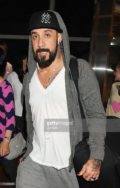 a man with headphones on is walking through an airport at night, wearing a baseball cap and sweatpants