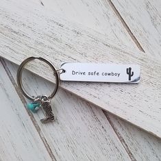 a keychain that says drive safe cowboy with a cactus charm hanging from it