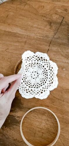 a person is making a doily on a wooden table