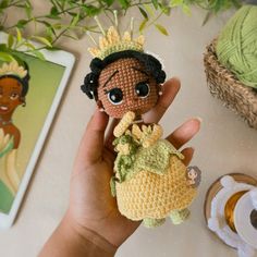 a crocheted doll with a crown on it's head is held up by someone