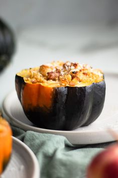 an eggplant stuffed with stuffing on a white plate next to other plates and apples