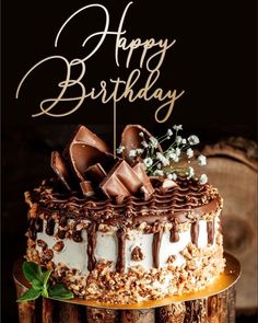 a birthday cake with chocolate frosting and flowers on top is sitting on a wooden table