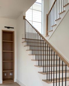 an empty room with a book shelf under the stair railing and open shelves on either side