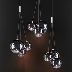 four lights hanging from the ceiling in a room with black walls and flooring, one is