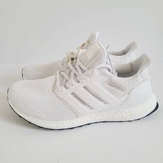 a pair of white adidas running shoes on a white surface with no one in the photo