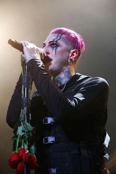 a man with pink hair and piercings holding a microphone