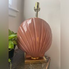 a pink vase sitting on top of a table next to a potted plant