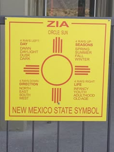 a yellow sign that is on the side of a metal fence and says, new mexico state symbol