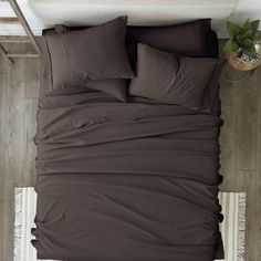 a bed with black sheets and pillows in a room