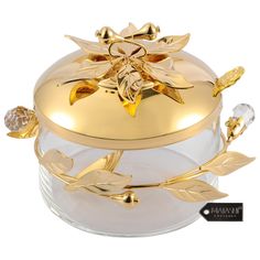 a gold plated box with leaves and flowers on the lid is sitting on a white surface