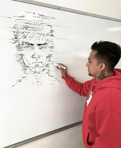 a man writing on a whiteboard with his hand in front of him and another drawing behind him