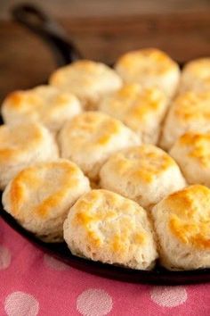 a pan filled with biscuits sitting on top of a pink table cloth covered in polka dot