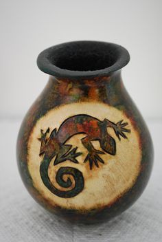 a brown and black vase sitting on top of a table