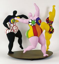 two figurines are standing next to each other on a wooden stand with white background