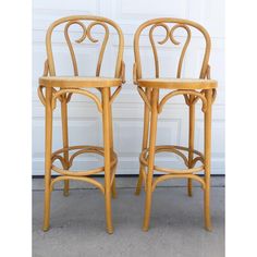 two wooden chairs sitting next to each other in front of a garage door