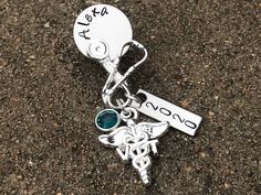 "Custom made pin for pinning ceremonies for an RN, NP, MA, LPN, LVN, BSN, SLP, DNP, PA, PTA, OTA, FNP, RT, PT, DPT, DNP, CNA, ADN, MD, and many many more! This beautiful shaped brooch/pin made with very unique design Hanging from the bottom is a VT caduceus charm and a birthstone charm with a disc hand stamped with the name of your choice. These pin it self is about 1 & 1/2 inch long but i did i hung charm on it so it will be about 2&1/2 inch after finished . Makes a great graduation gif Personalized Silver Badge Reel For Gift, Personalized Silver Badge Reel As Gift, Customizable Silver Badge Reel As Gift, Personalized Silver Badge Reel Gift, Customizable Silver Badge Reel Gift, Personalized Silver Lapel Pin For Gift, Personalized Silver Lapel Pin As Gift, Personalized Silver Lapel Pin Gift, Personalized Silver Pins For Anniversary